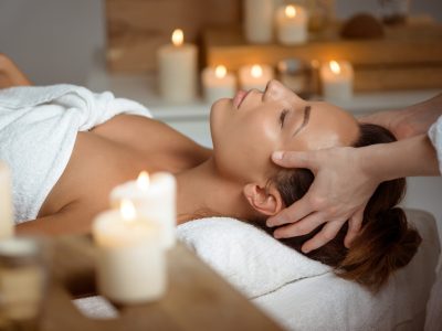 Young beautiful brunette girl having face massage relaxing in spa salon. Eyes closed. Copy space.